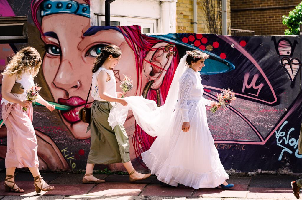 Bride walks past Brighton graffiti wall on the way to her wedding