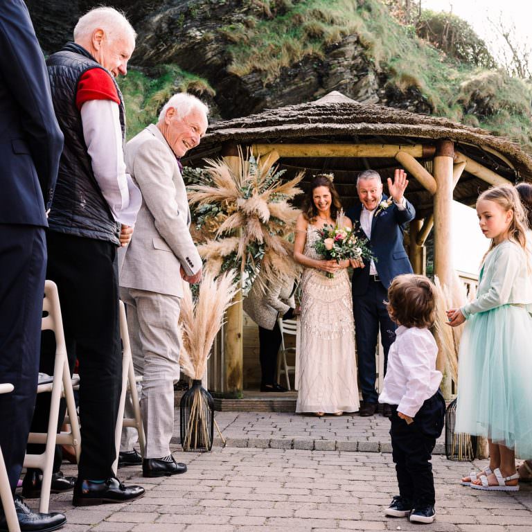 Groom waves to pageboy during Tunnels Beaches wedding ceremony