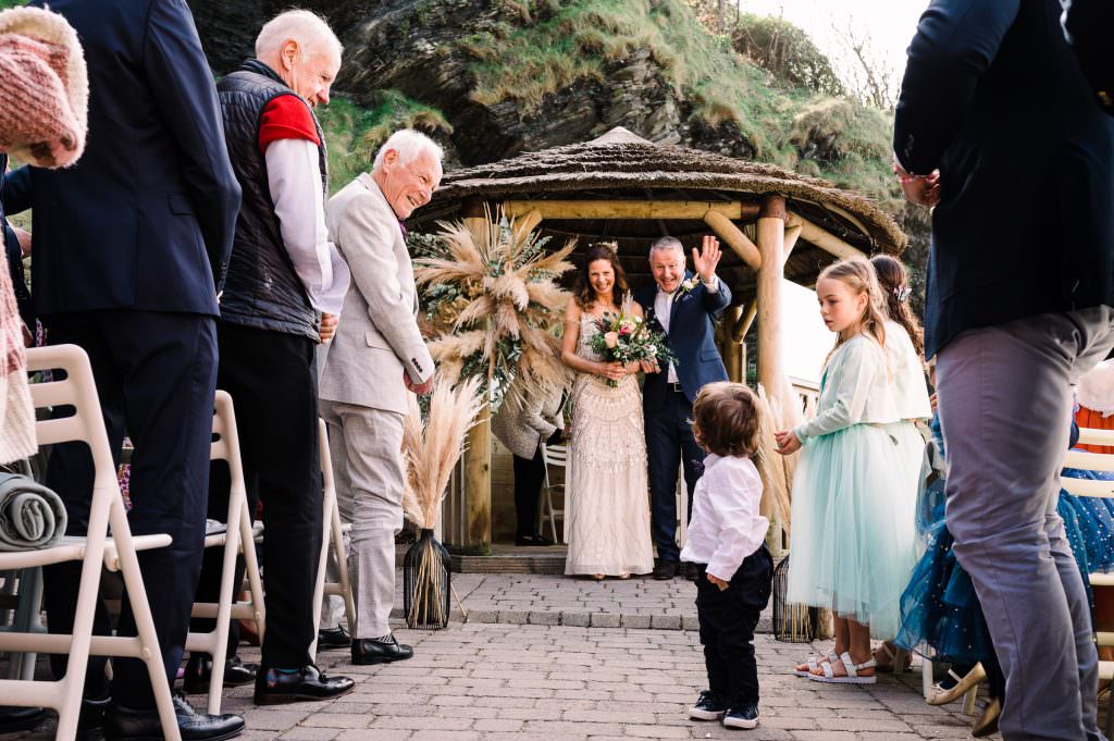 Just married couple at Tunnels Beaches wave to pageboy