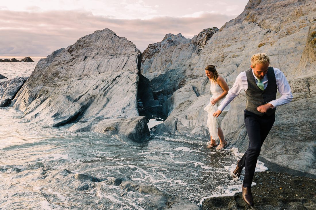 Bride and groom jumnp the waves at Tunnels beaches wedding