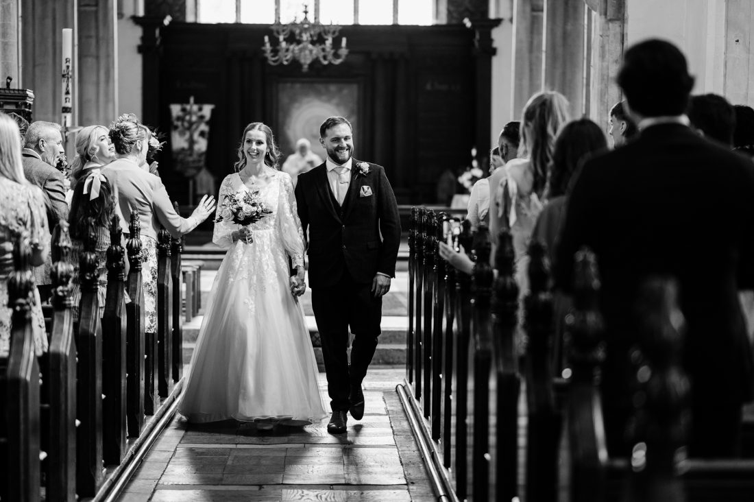 Black & White photo of bride and groom exiting their church wedding