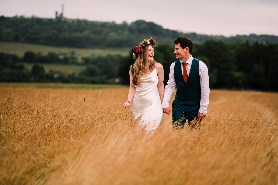 Bride and groom walking through the fields at Cissbury Barns wedding