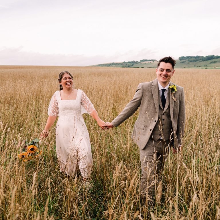 Bride and groom walk through the fields at their Long Furlong Barn wedding