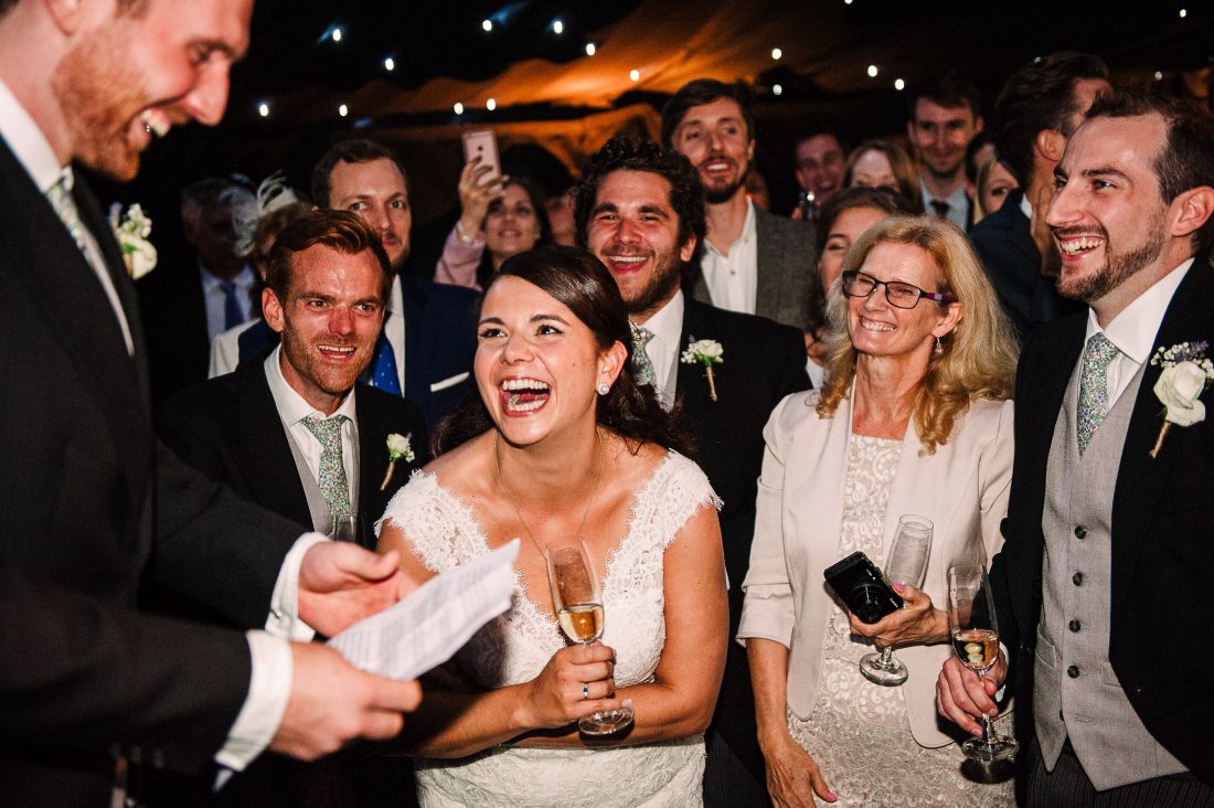 Bride laughs during speech at Sussex garden marquee wedding