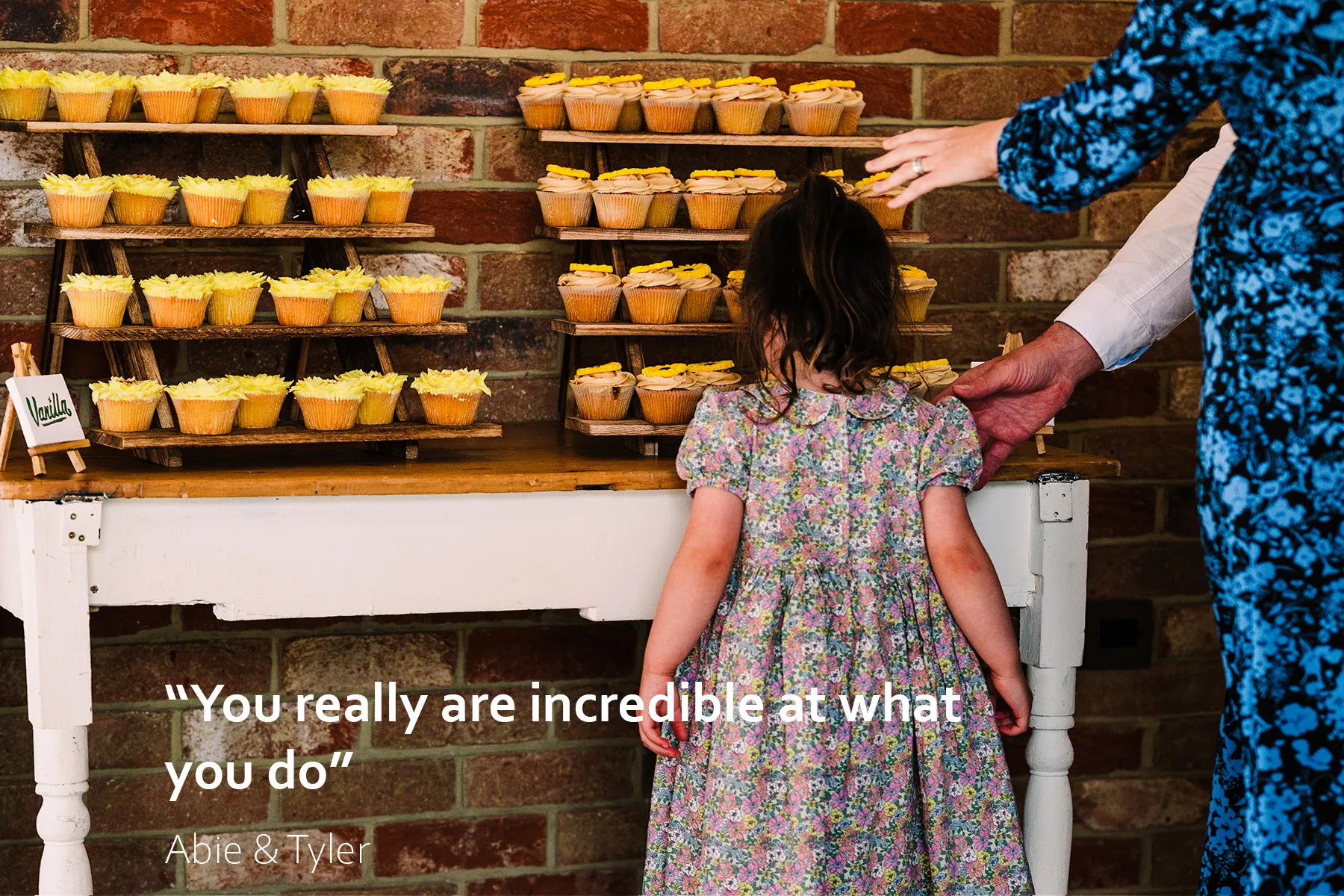 A young girl leans forward to smell cupcakes at Long Furlong Barn wedding