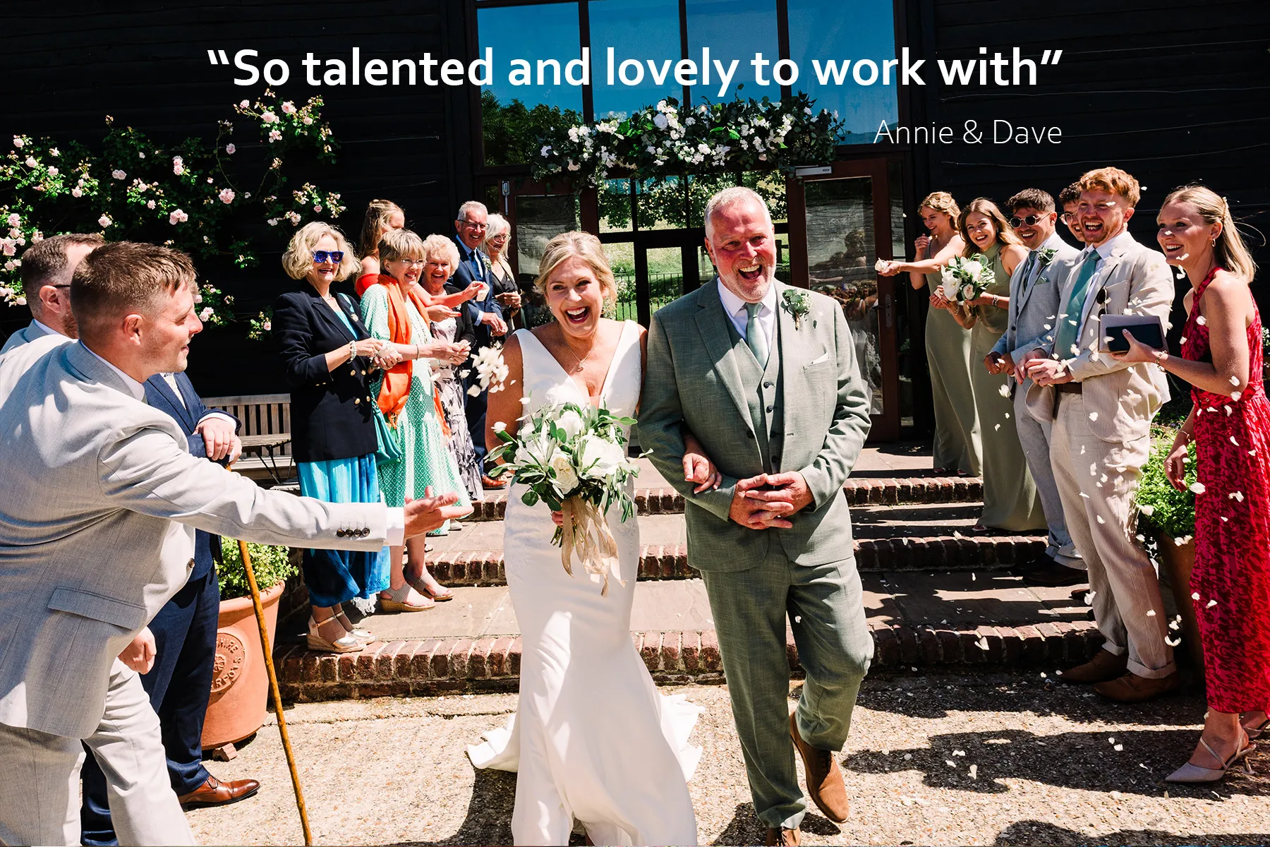 Mature bride & groom walk through a confetti arch at their Upwaltham Barns wedding