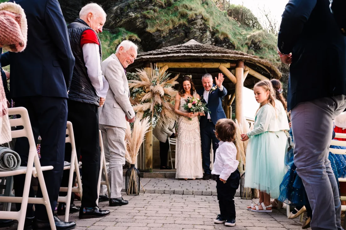 Just married couple at Tunnels Beaches wave to pageboy