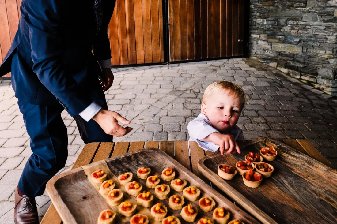 Guest supervises young child with canapés at Tunnels Beaches wedding
