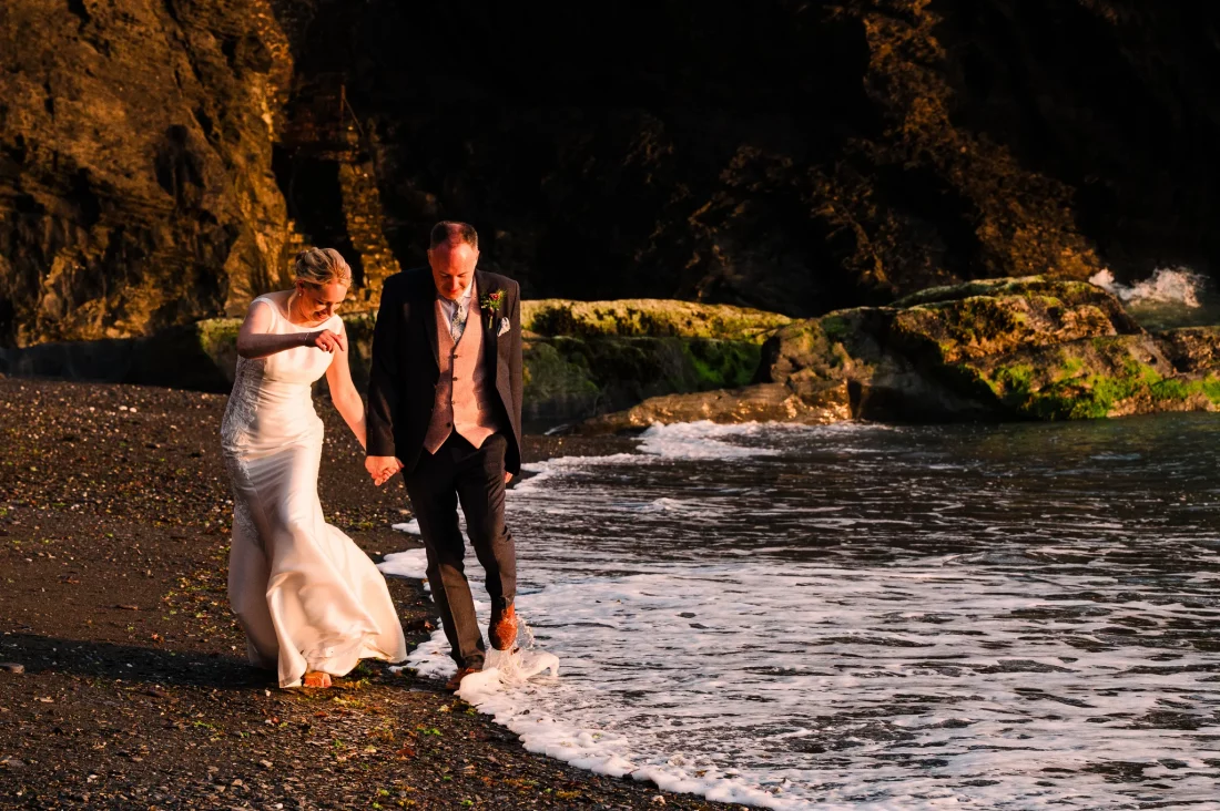 Bride and groom dodge the waves at Tunnels Beaches wedding