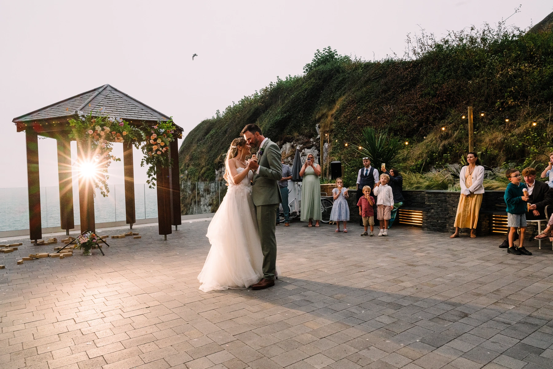 Bride and Groom enjoy their first dance on the courtyard at Tunnels Beaches wedding venue, with the sea and cliffs in the background